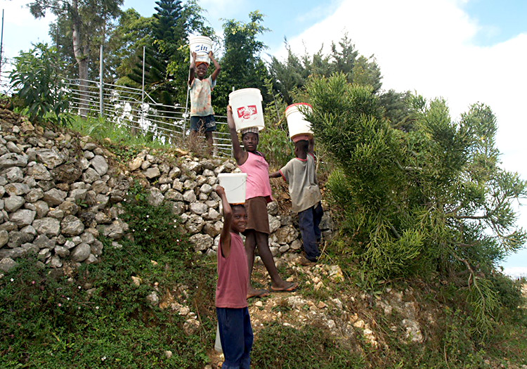 Children carry water buckets in the mountains.