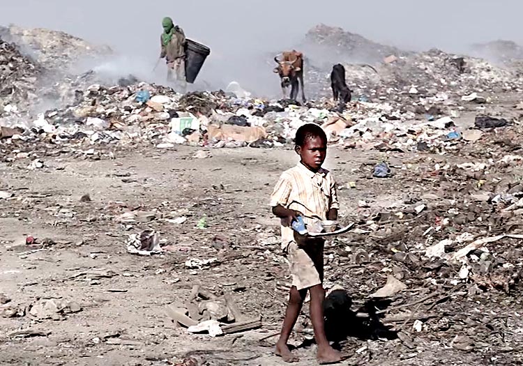 Young boy looking for food in the garbage dump.