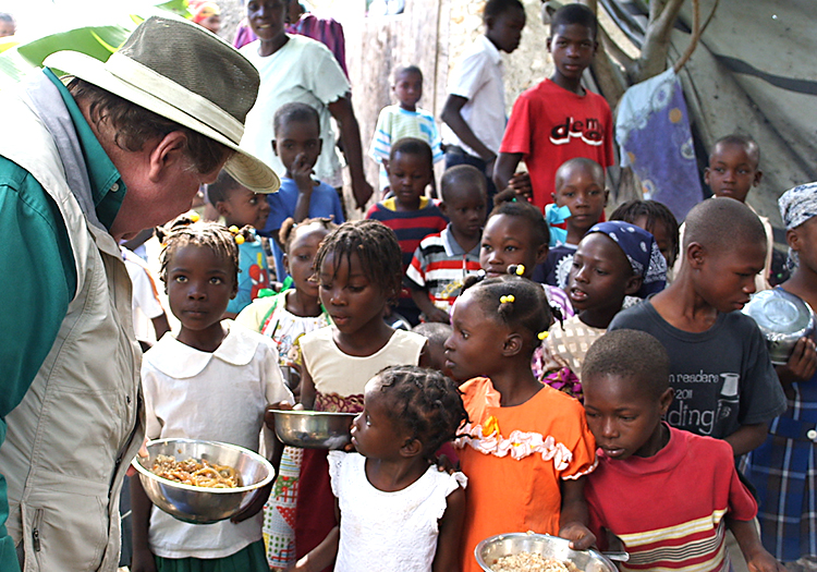 Bobby handing food to hurgry children in Haiti.