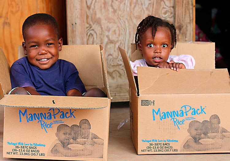 Happy Haitian children sitting in boxes from Feed My Starving Children.