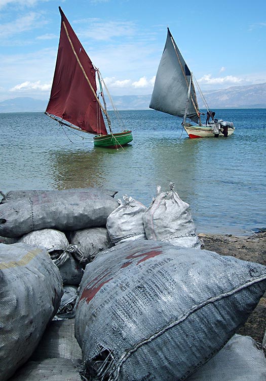 Loading bags of charcoal on sailboats to sell.