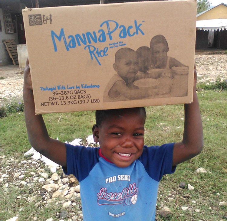 Young boy holding a box of food to take home.