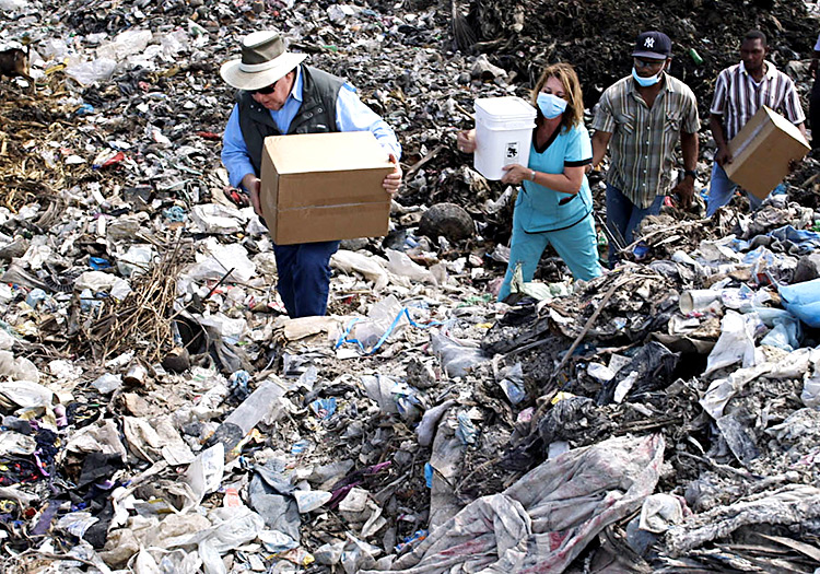 Bobby and Julie carry boxes of food through the Truittier Garbage Dump.