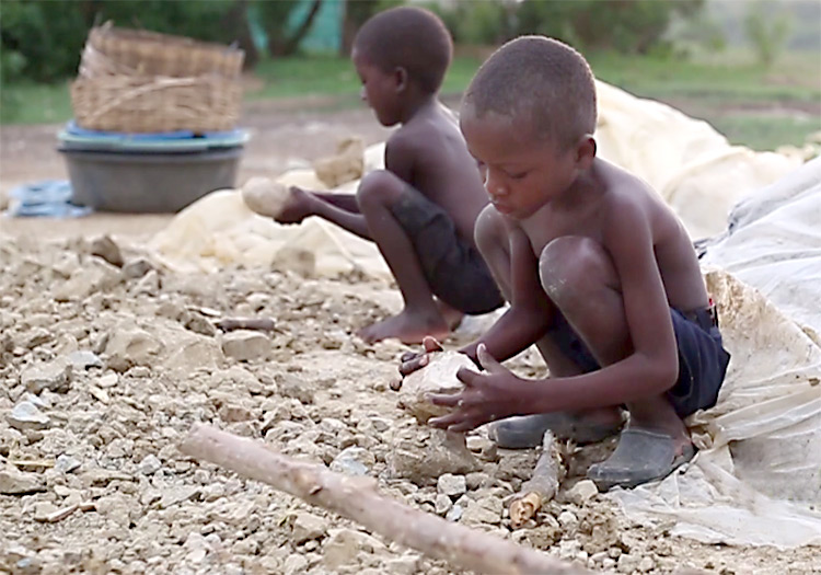 Young boys break up rock to make mud cookies.
