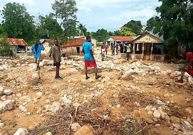 Haitians survey the damage of their village in Haiti