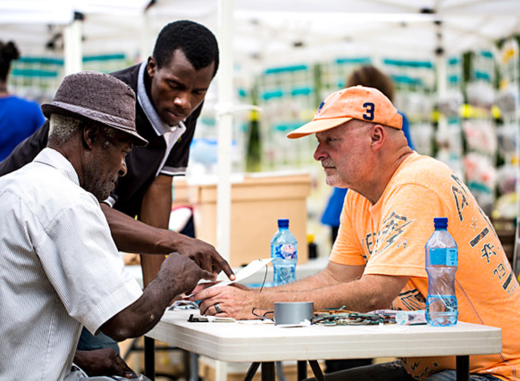 David George assisting elderly Haitin with new glasses