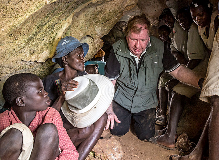 Bobby crawels through cave filled with Haitian families.