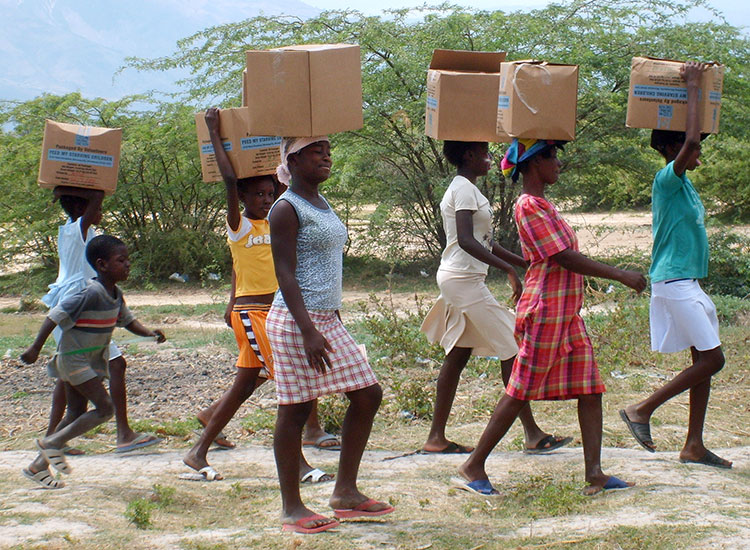 Haitian women carry their food boxes back to their homes.