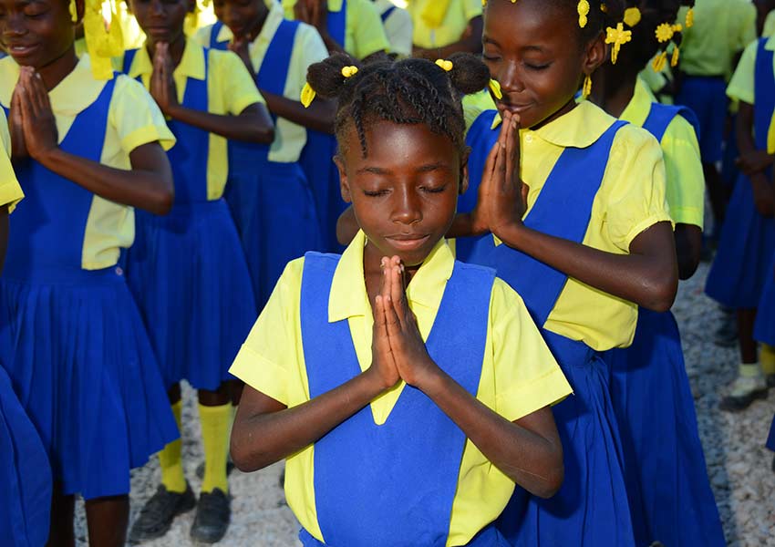 Students pray before the start of school each morning.