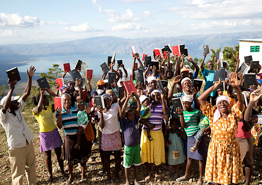 In the mountain village of Peyi Pouri, Haitians hold up their new Creole Bibles.