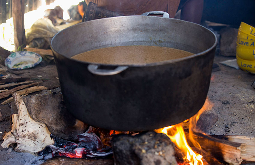 Food cooking in a big pot over a "3-rock cooking fire."