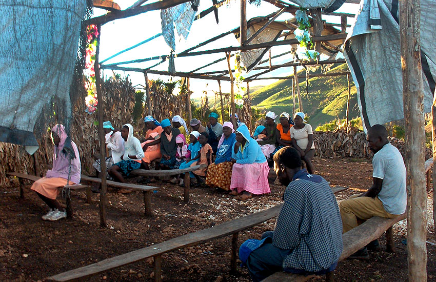 Haitians gather to listen to the Word of God in this tattered remains of a stick church with a ripped tarp as the roof.