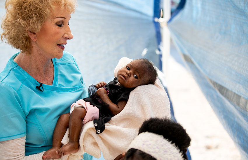 Sherry holds a young child suffering from Kwashiorkor malnutrition.