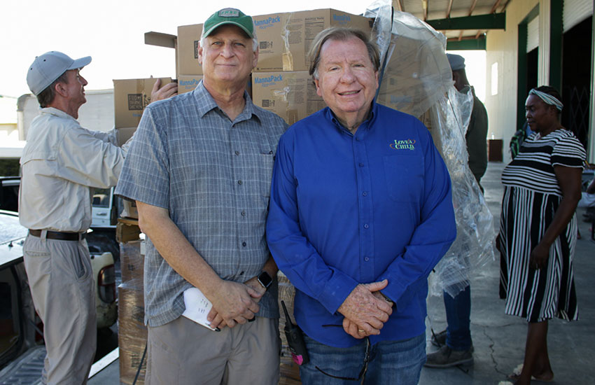 Mark Crea from Feed My Starving Children and Bobby watch the monthly food distribution.