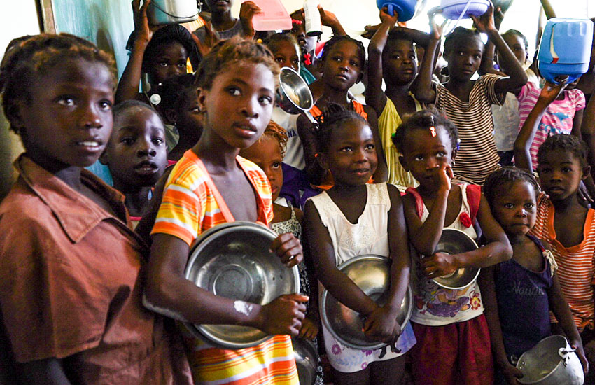 Hungry children wait to receive a bowl of hot, nourishing food.